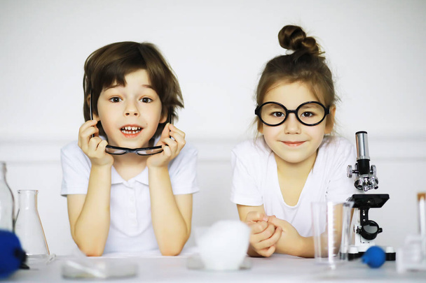 Two cute children at chemistry lesson making experiments isolated on white backgroun - 写真・画像