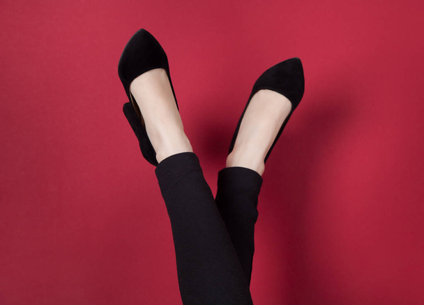 Gambe di donna in eleganti scarpe alte, su sfondo rosso. - Foto, immagini