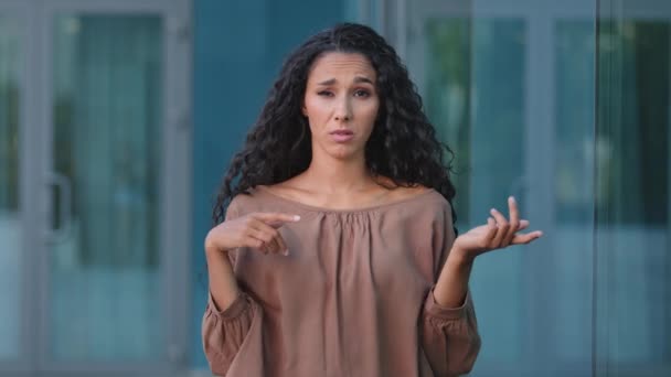 Portrait outdoors close up hispanic bored angry woman disappointed caucasian girl showing bla-bla-bla hands blah blah gesture and rolling eyes covers ears standing in city refuses to listen gossip - Footage, Video