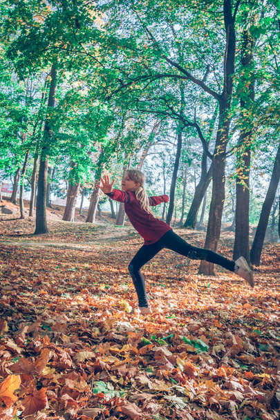 ragazza felice che balla tra le foglie nel parco autunnale - Foto, immagini