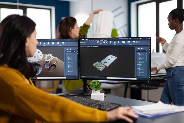 Ingegnere industriale donna che lavora al pc con due monitor, schermi che mostrano software CAD - Foto, immagini