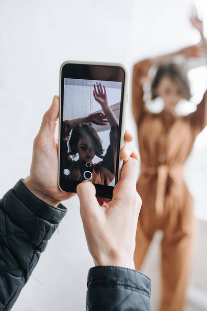 Male hands taking photo of a model with smartphone. Selective focus on screen with sensual brunette. Real one is blurred. - Valokuva, kuva