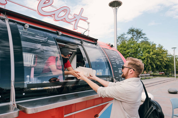 Giovane uomo occupato l'acquisto di fast food in camion strada rossa - Foto, immagini