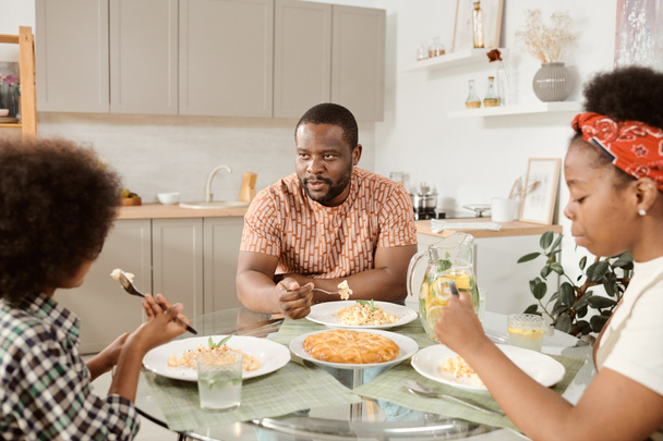 Jeune famille assise à table et dînant dans la cuisine - Photo, image