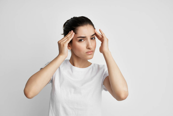 brunette in a white t-shirt holding her head migraine stress depression - Fotografie, Obrázek