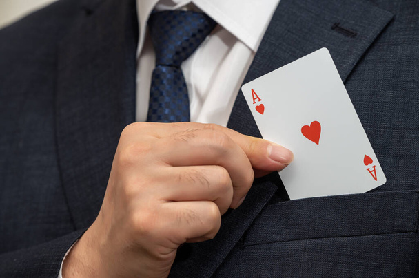 Άσσος κάρτα στο χέρι ενός επιχειρηματία σε ένα κοστούμι. - Φωτογραφία, εικόνα