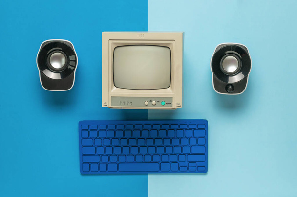 Um monitor, um teclado e dois alto-falantes de computador em um fundo azul de dois tons. Equipamento vintage elegante. Depósito plano. - Foto, Imagem
