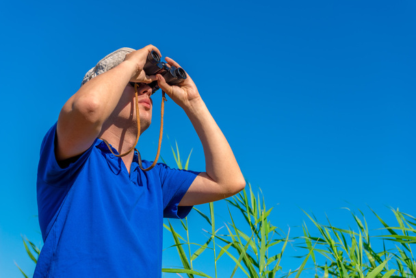 Mann mit Fernglas untersucht Vogel am Himmel - Foto, Bild