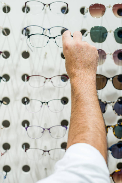 Различные очки на стене в магазине очков. - Фото, изображение