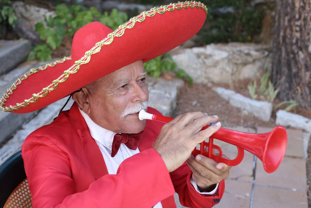 portrait en gros plan d'un bel homme âgé en costume rouge avec sombrero à l'extérieur - Photo, image