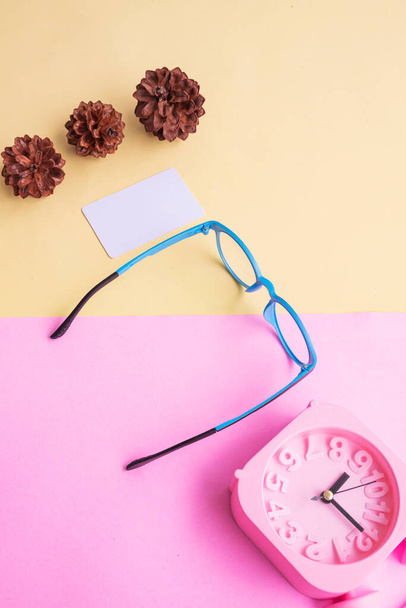 Круглі окуляри на фотографії в мінімальному літньому стилі на рожевому і жовтому фоні. Alarm Clock , Pine Tree Flowers , Business Card - Фото, зображення