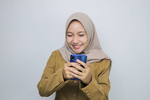 Happy government worker women when using a smartphone. PNS wearing khaki uniform. - Foto, afbeelding