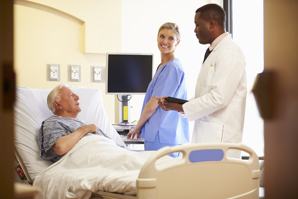 Medical Team Meeting With Senior Man In Hospital Room - Valokuva, kuva