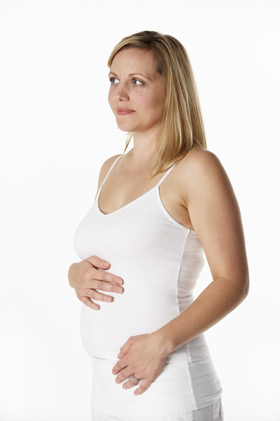 Studio Portrait Of 4 months Pregnant Woman Wearing White - Foto, imagen
