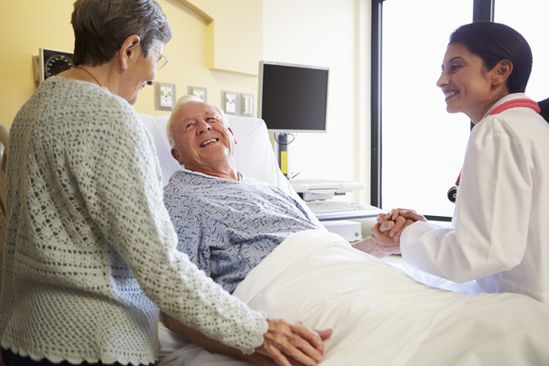 Female Doctor Talking To Senior Couple In Hospital Room - Photo, image