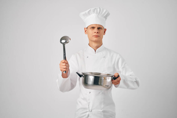 Şef üniformalı bir adam elinde tavayla profesyonel restoranlar pişiriyor. - Fotoğraf, Görsel