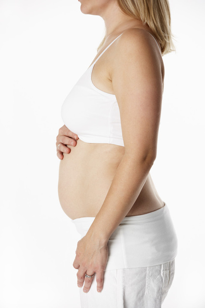 Close Up Studio Portrait Of 4 months Pregnant Woman Wearing Whit - 写真・画像