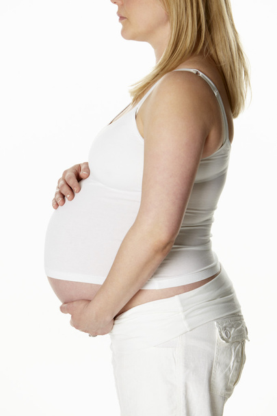 Close Up Studio Portrait Of 8 Months Pregnant Woman Wearing Whit - Foto, afbeelding