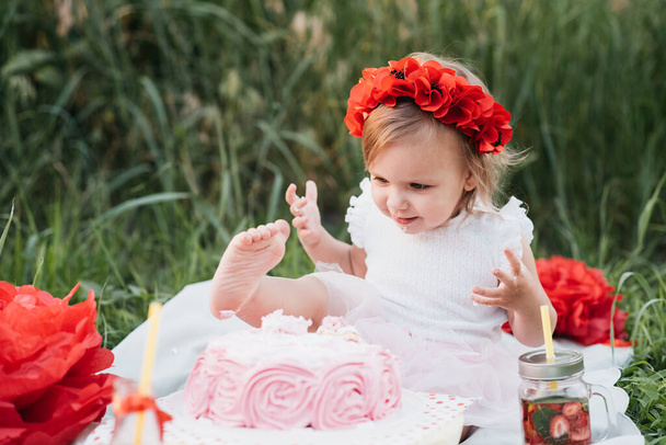 second birthday of little girl. Two years old girl sitting near celebration decorations and eating her birthday cake. Cake Smash - Fotografie, Obrázek