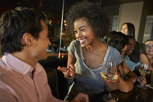 Couple Enjoying Drink At Bar With Friends - Zdjęcie, obraz