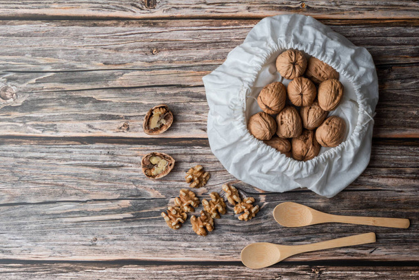 Peeled walnuts on wooden background and sack of walnuts in shell - Foto, imagen