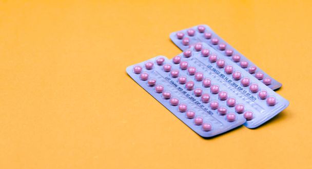 Blister packs of contraceptive pills on yellow background. Hormone pills for treatment hormone acne. Birth control pills. Estrogen and progesterone hormone pills. Pharmacy banner. Prescription drugs. - Zdjęcie, obraz