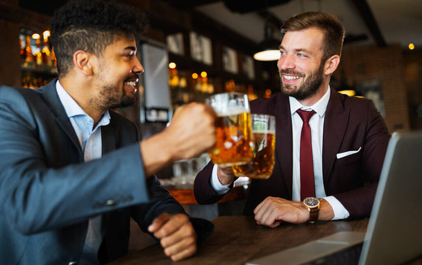 Business people drink beer after work. Businessmen enjoy a beer at a pub - Фото, изображение