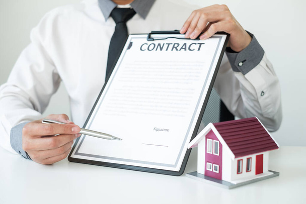 Agenten, die in Immobilieninvestitionen tätig sind, halten den Schlüssel für die Hausratversicherung in der Hand und unterzeichnen Verträge in Übereinstimmung mit den Verträgen über den Hauskauf, die Käufe für Kunden genehmigen.. - Foto, Bild