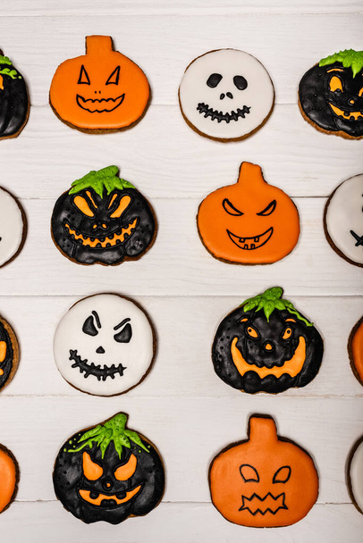 bovenaanzicht van zelfgemaakte en griezelige halloween koekjes op wit oppervlak  - Foto, afbeelding