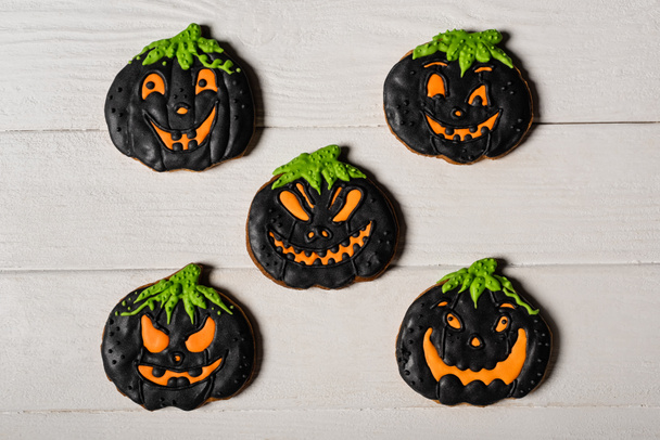 flay lay with black and spooky pumpkin shape halloween cookies on white surface - Foto, afbeelding
