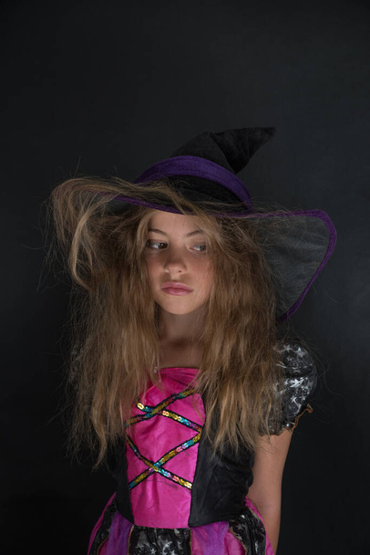 Dziewczyna przebrana za wiedźmę i kapelusz z szerokim rondem na Halloween.. - Zdjęcie, obraz