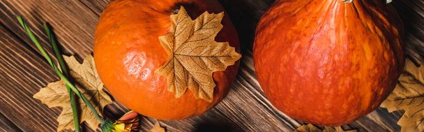 木製の表面にオレンジ色のカボチャの近くの秋の葉のトップビュー、バナー - 写真・画像