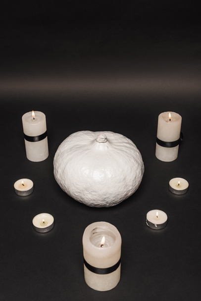 white pumpkin near burning candles on black background  - Foto, Imagem
