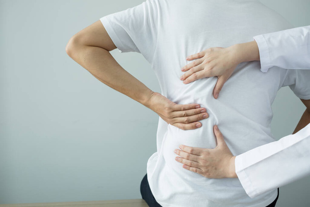 Fisioterapeutas femeninas brindan asistencia física a pacientes masculinos con lesiones en la espalda masajes de espalda para la relajación y la recuperación muscular en el centro de rehabilitación. - Foto, imagen