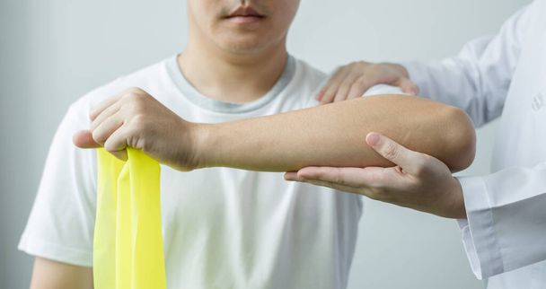 Les physiothérapeutes féminines aident les patients masculins souffrant de blessures aux bras, de traction des bras, de relaxation musculaire dans le centre de réadaptation. Concepts de physiothérapie. - Photo, image