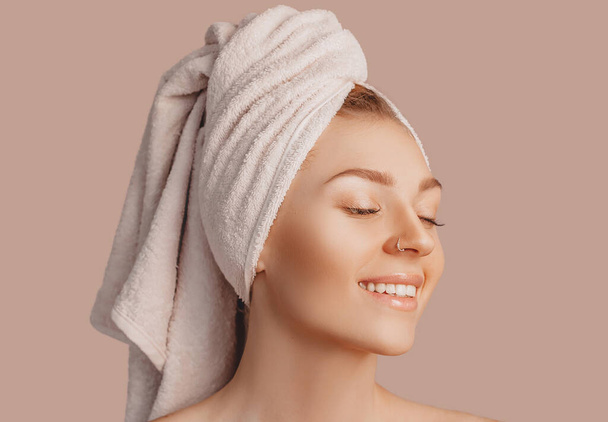 Beautiful sensual young girl with clean skin on a beige background with a mockup. Topless woman in a towel. The concept of spa treatments, natural beauty and care, youth, cream and mask, freshness - Foto, immagini