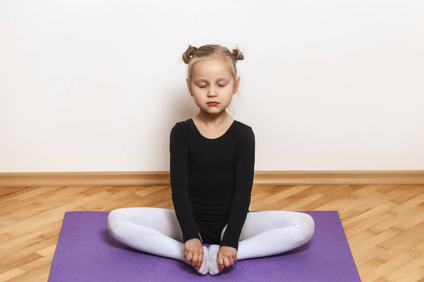 Meditation little girl with closed eyes in lotus position. hild does stretching at home training - Photo, Image