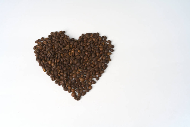 A large heart made of coffee beans on a white background. - Valokuva, kuva