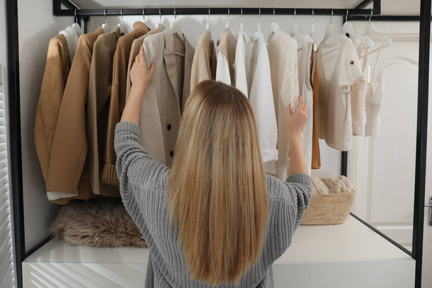 Young woman choosing outfit in dressing room, back view - Foto, afbeelding