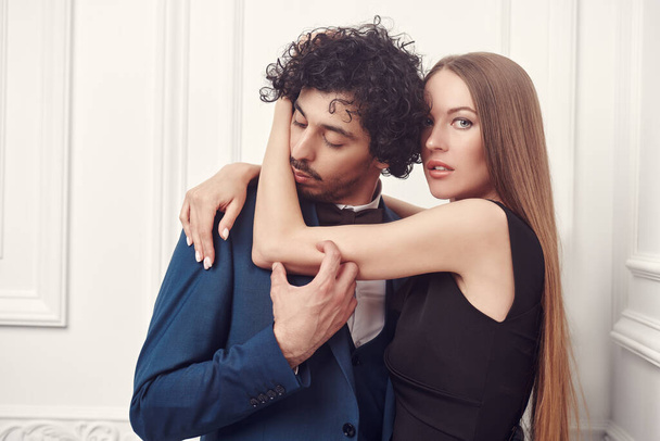 Love and passion. Beautiful young woman hugs tenderly her beloved man. Beautiful couple in love wearing evening clothes. Fashion shot. - Фото, зображення