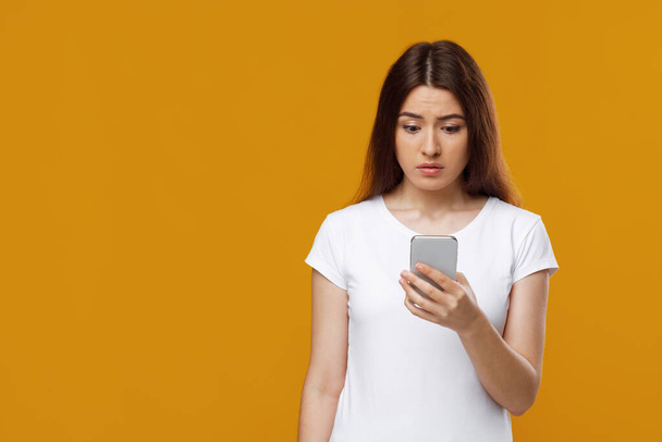 Расстроенная молодая женщина с помощью мобильного телефона, копировальное пространство - Фото, изображение