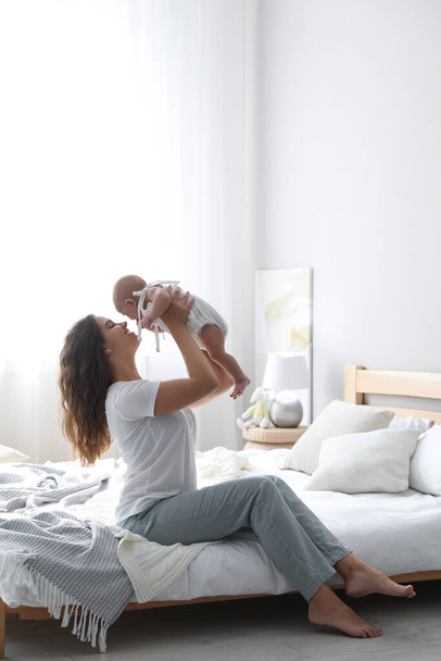 Happy young mother with her cute baby on bed at home - Foto, immagini