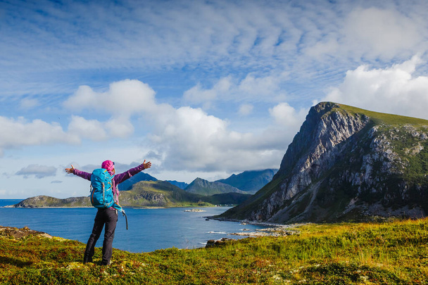 Woman hiker enjoying at the top of the mountain and looking at incredible views of a Norwegian fjord, Lofotens. Travel, adventure, healthy lifestyle concept - Zdjęcie, obraz