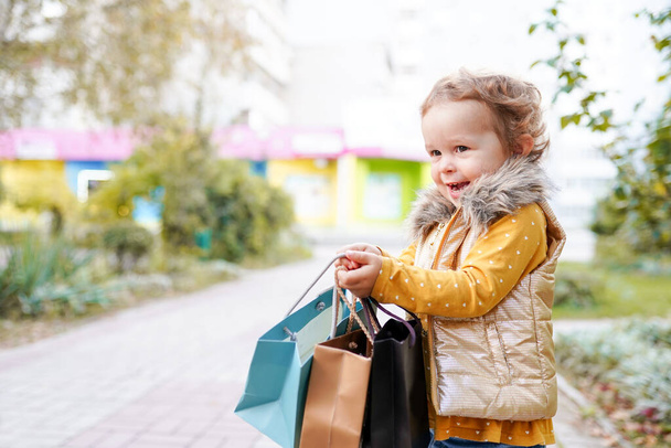 子供の女の子で秋のオレンジの布でショッピングバッグ屋外 - 写真・画像
