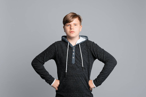 Впевнений хлопчик-підліток в светрі позує на сірому фоні. Студійний знімок. Мода підлітків
 - Фото, зображення
