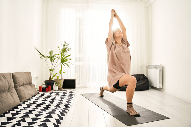 Woman practicing yoga in warrior pose - Fotografie, Obrázek