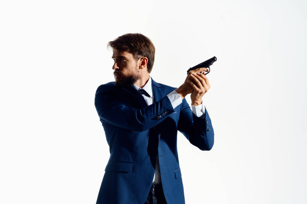 Ο άνθρωπος με ένα πιστόλι στο χέρι ντετέκτιβ έγκλημα δολοφόνος φως φόντο - Φωτογραφία, εικόνα