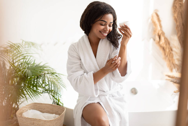 African Woman Moisturizing Body And Hands Applying Cream In Bathroom - Photo, Image
