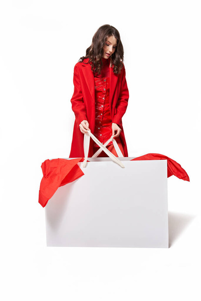 Woman in red clothes holding big white shopping bag - Foto, afbeelding