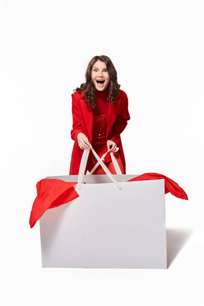 Woman in red clothes holding big white shopping bag - Фото, изображение